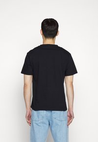 Černé bavlněné tričko s krátkými rukávy a kulatým výstřihem, v kombinaci s světle modrými džíny. Design je jednoduchý a klasický.