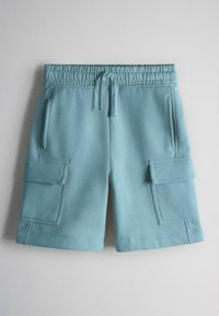 Shorts bleu clair jusqu'aux genoux avec taille élastique, cordon de serrage, poches latérales et grandes poches cargo à rabat sur chaque jambe.