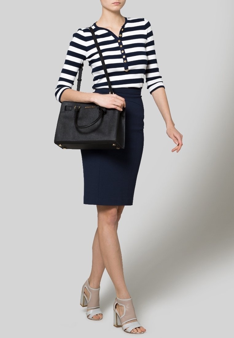 Sac fourre-tout noir, jupe crayon bleu marine et chemise rayée bleu marine et blanche avec des boutons. Talons transparents avec des brides à la cheville. Design simple et structuré.