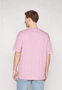 Kortærmet t-shirt med rund hals i lys pink bomuld. Løs pasform med lige kant. Bagfra er der ingen trykte detaljer eller accentuer.