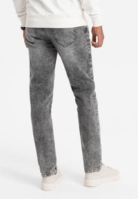 Harmaat farkut, joissa on haalistunut pinta, viisi taskua, kontrastiväriset ompeleet ja slim fit -leikkaus. Yhdistetty vaaleanvärisiin tennareihin.