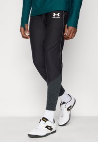 Τα μαύρα αθλητικά παντελόνια διαθέτουν υφασμένους πράσινους τόνους στα κάτω πόδια, εφαρμοστή γραμμή και κεντημένο λευκό λογότυπο της μάρκας στη μέση.