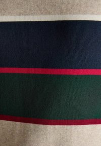 Strickstoff mit horizontalen Streifen in Beige, Marineblau, Rot und Dunkelgrün, der Textur und Farbkontraste zeigt.