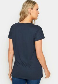 Navy blue t-paita, jossa on rento leikkaus, lyhyet käärityt hihat ja pyöreä pääntie. Pehmeä kangas, jossa on sileä pinta.