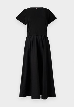 Robe noire en tissu léger avec des manches courtes et un col rond. La jupe est froncée à la taille, créant une silhouette fluide.