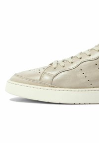 Svijetlosmeđi kožni tenisice s perforiranim detaljima, zaobljenim vrhom, ravnim bijelim potplatom i matching vezicama. Glatka tekstura s suptilnim šavovima.