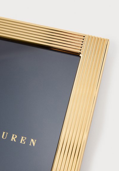 Arany fém képkeret recézett élekkel, masszív fekete háttérrel és az alján dombornyomott felirattal.