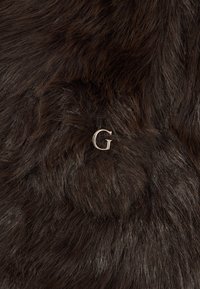 Mørkebrun faux fur med en blød tekstur, med et sølvfarvet "G" logo akcent indlejret i materialet.