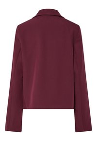 Set bagfra af en langærmet, dyb burgundy blazer med en enkel krave og en lige kant.