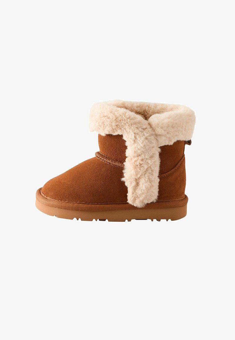 Kastanjebruine suede enkelboot, voorzien van een zachte beige faux-fur boord. Ronde neus, platte zool en eenvoudige stikdetails langs de naden.