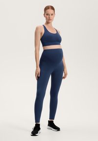 Námořnickomodrý těhotenský sportovní set obsahující podporující sportovní podprsenku a legíny s vysokým pasem, vyrobený z hladké, pružné tkaniny.