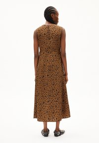Brown sleeveless dress with a spotted pattern, featuring a fitted bodice, flared skirt, and a back zipper. Shiny accents on shoes.