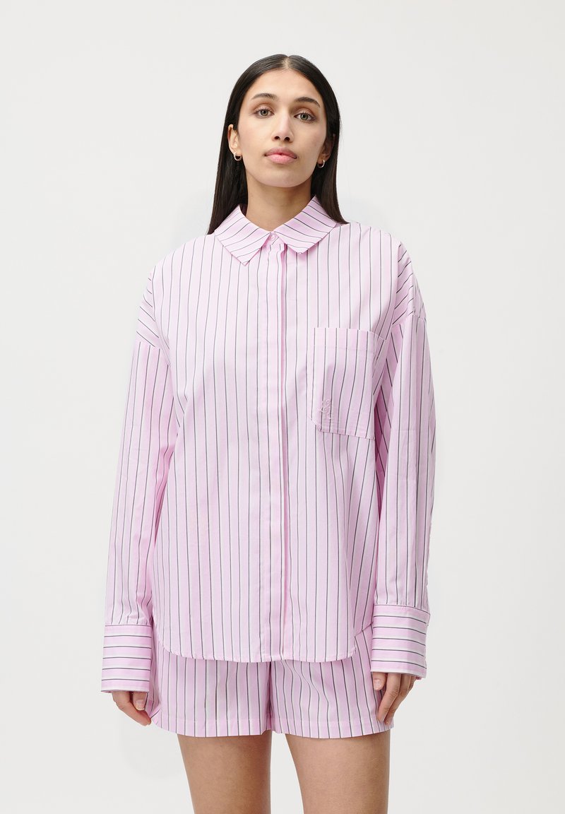 Camicetta a righe rosa con bottoni e maniche lunghe, dotata di tasca frontale, abbinata a pantaloni corti a righe rosa. Tessuto morbido, vestibilità comoda.