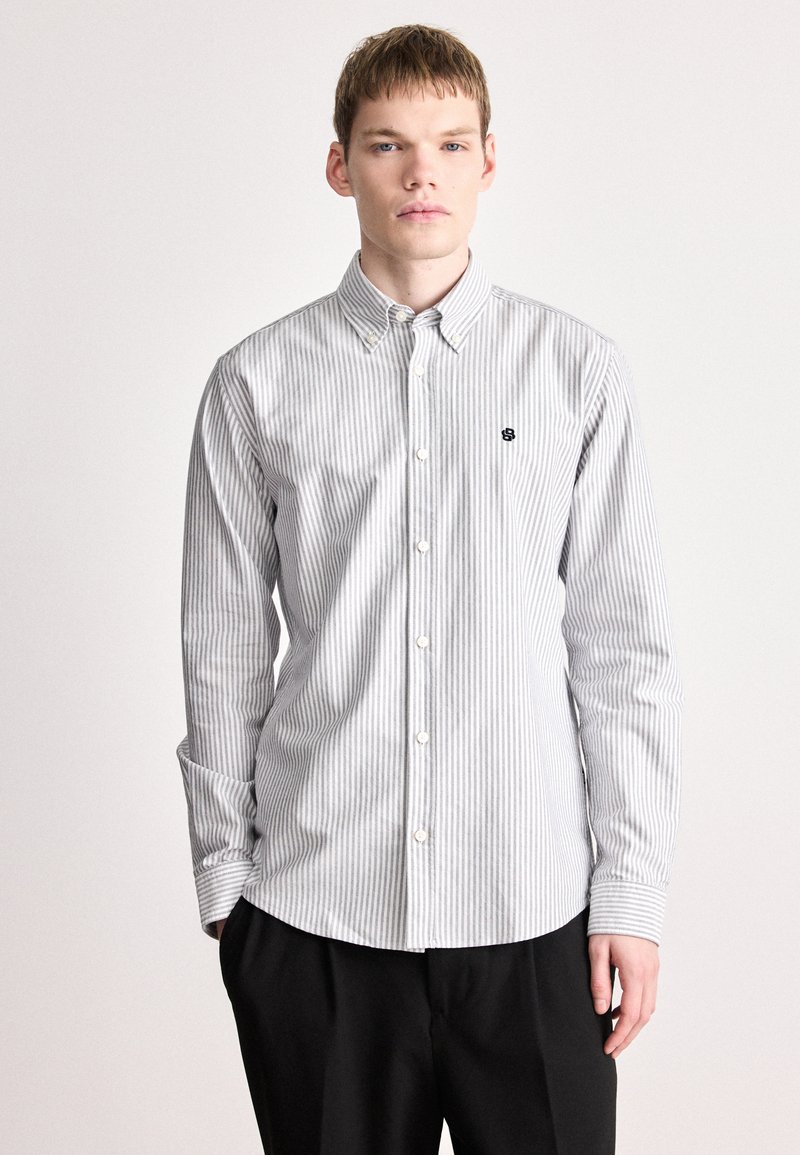 Πουκάμισο με κουμπιά και ρίγες σε γκρι και λευκό. Διαθέτει κλασικό γιακά, μακριά μανίκια και μικρό μαύρο λογότυπο στο στήθος. Υλικό από βαμβάκι.