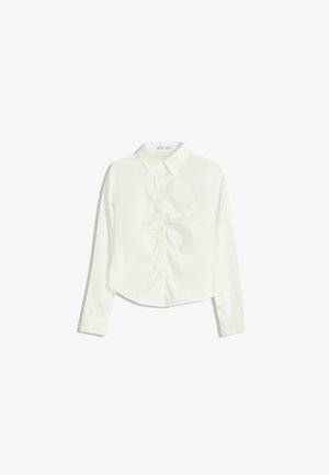 Valkoinen, pitkähihaisen nappipaidan, jossa on kaulus. Paidassa on hienovaraisia rypytyksiä edessä ja se on lyhennetty helmasta.