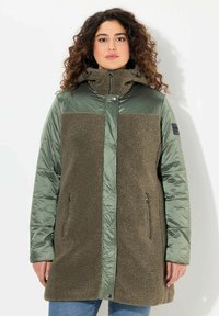 Olivgrön ytterklädsel med en kombination av mjuk fleece och glänsande tyg, med hög krage, dragkedjefickor och avslappnad passform.