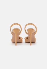 Sandálias de salto alto bege com um acabamento liso e mate, apresentando uma faixa circular para o tornozelo e um elegante salto stiletto fino, com um design de biqueira aberta.