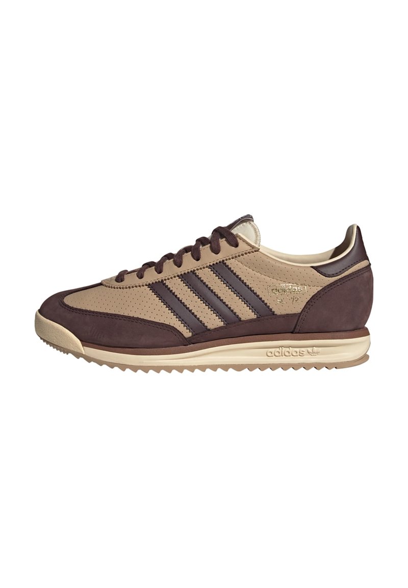 Chaussure de sport marron et beige en cuir lisse et en suède, avec des détails perforés et trois rayures foncées sur le côté.