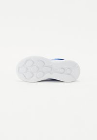 White rubber sole with textured grip, featuring a blue upper section. The design includes rounded shapes and hexagonal patterns for traction.