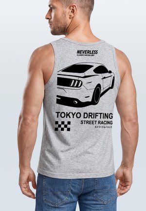 Mann trägt ein graues ärmelloses Shirt mit schwarzer Grafik eines Sportwagens und dem Schriftzug „Tokyo Drifting Street Racing“ auf dem Rücken.