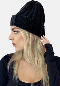 Beanie nero a coste con un alto corone e risvolto. La texture è morbida, con linee verticali e una leggera lucentezza.