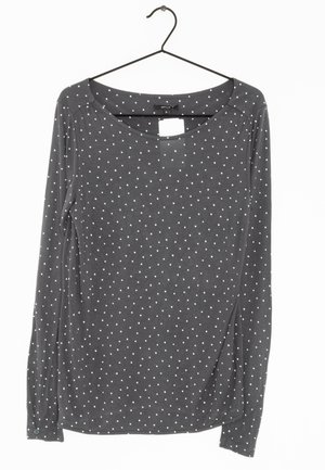 Ciemnoszara koszula z długim rękawem w białe kropki wisząca na czarnym wieszaku na białym tle.