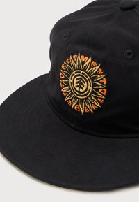 Μαύρο καπέλο μπέιζμπολ με κεντητό σχέδιο ηλίανθου σε κίτρινο και πορτοκαλί, τοποθετημένο στο κέντρο της μπροστινής πλευράς.