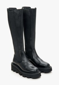 Black knee-high boots with a smooth leather finish, elastic side panels, and a chunky platform sole featuring a textured tread.