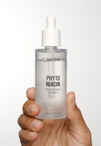 Genomskinlig glasflaska med ett vitt pipettlock. Etiketterna visar "NACIFIC" och "PHYTO NIACIN BRIGHTENING ESSENCE." Volym: 50 ml.
