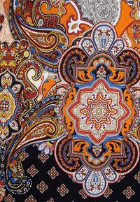 Patrón de paisley colorido con detalles en naranja, azul y blanco sobre un fondo negro. Presenta intrincados diseños florales y geométricos.