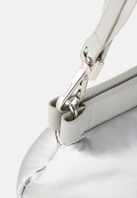 Borsa in pelle grigia con una texture liscia e lucida. Presenta una clip e un manico in metallo argentato, con cuciture evidenti e una forma arrotondata.