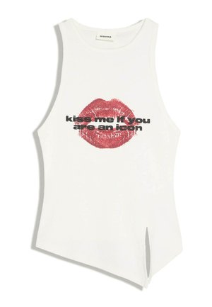 Haut sans manches blanc avec un imprimé de lèvres rouges et un texte noir indiquant "kiss me if you are an icon,", avec un ourlet asymétrique et une fente latérale.