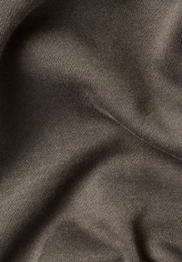 Tessuto lavorato a maglia marrone, con una consistenza morbida e una leggera lucentezza, caratterizzato da sottili costine e pieghe delicate, che mostrano una superficie liscia e continua.