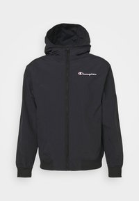 Černá kapucňová bunda vyrobená z lehkého materiálu, s plným zipem, elastickými manžetami a malým bílým a červeným logem Champion na hrudi.