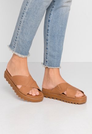 Brown cross-strap sandals with rubber soles featuring a textured grip. Open-toe design and a smooth, matte finish on straps.