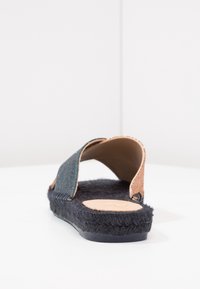 Sandal na klínku s horní částí z texturované tmavě modré látky, se dvěma otevřenými popruhy a světle hnědou stélkou. Disponuje fuzzy černou podrážkou pro pohodlí.