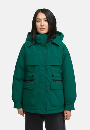 Chaqueta aislante verde con capucha, que cuenta con dos grandes bolsillos frontales, cierres con cremallera y un corte relajado. Textura de tela suave.