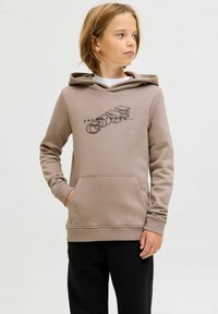 Sudadera marrón con un estampado gráfico. Textura suave, bolsillo frontal y capucha con cordón. Combinada con pantalones negros para un look completo.