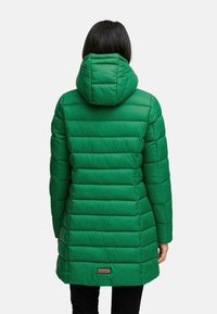 Cappotto lungo verde, imbottito e con cappuccio, caratterizzato da righe verticali, una leggera lucentezza e una toppa con marchio vicino all'orlo.