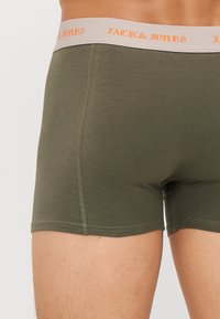 Dunkelgrüne Boxer-Shorts aus weichem Material mit einem hellgrauen elastischen Bund, der "JACK & JONES" in orangefarbener Schrift trägt.