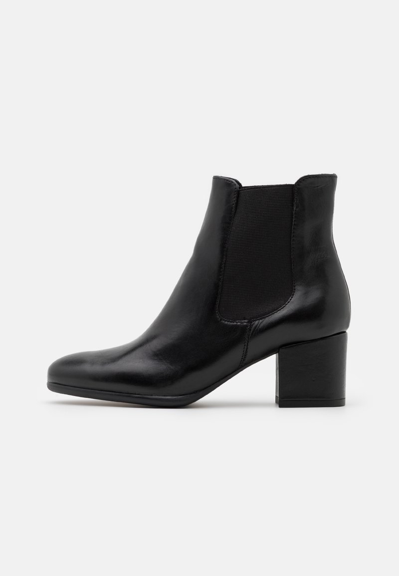 Bottine en cuir noir avec talon bloc et panneau latéral élastique pour un enfilage facile, présentée sur un fond clair uni.