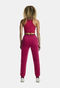 Lys pink sport bh og matchende joggers med elastisk talje. Joggers har sidelommer og tapered manchetter. Blød tekstur, afslappet pasform.