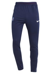 Pantalones deportivos slim-fit azul marino con cintura elástica, logo del Paris Saint-Germain en el muslo izquierdo y swoosh blanco de Nike en el muslo derecho.