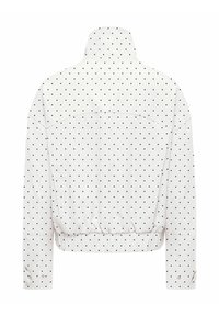 Veste blanche à pois noirs, col montant, taille élastique et poignets boutonnés, vue de dos sur fond uni.