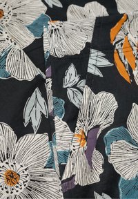 Black fabric with a floral pattern featuring large white and pastel flowers, accented with orange and turquoise leaves. Textured surface.