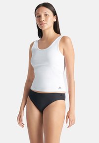 Witte geribde tanktop met een ronde hals, gecombineerd met zwarte bikinionderdelen. Heeft het Adidas-logo op de linksonderkant van de top.