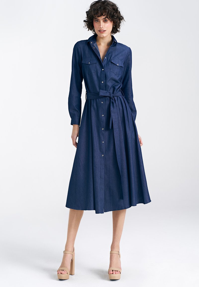 Granatowa sukienka midi z denimu zapinana na guziki, z długimi rękawami, dwiema kieszeniami na piersi, paskiem w talii i zwiewnym dołem.