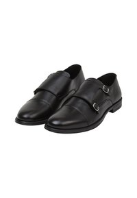 Chaussures en cuir noir avec une texture lisse, dotées de deux sangles réglables à boucle, d'un bout rond et d'un petit talon carré.