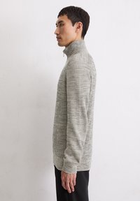 Grau strukturierter Pullover mit hohem Kragen und Reißverschluss, der ein Rippmuster und lange Ärmel aufweist.