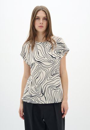 Top a maniche corte in crema con linee ondulate nere; vestibilità rilassata e tessuto morbido; scollatura rotonda; progettato con un motivo astratto e organico.